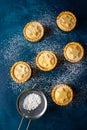 British Christmas Pastry Home Baked Powdered Mince Pies with Apples Raisins Nuts Apricot Jam Filling Scattered on Dusted Dark Blue Royalty Free Stock Photo