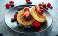 British Crumpets breakfast with blueberries, strawberries, blackberries, raspberries drizzled with icing sugar Royalty Free Stock Photo