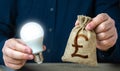 British pound sterling money bag and burning idea light bulb in the hands of a man. Royalty Free Stock Photo