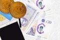 20 British pounds bills and golden bitcoins with smartphone and credit cards. Cryptocurrency investment concept. Crypto mining or