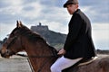 Handsome male rider on horse with flatcap in front of old castle