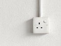 British style three pin electrical socket with switch mounted on a textured white wall and conduit pipe. Royalty Free Stock Photo