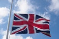 British union flag flying against a blue cloudy sky in a flag pole Royalty Free Stock Photo