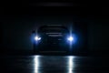 Black sports car with lights on in a dark garage Royalty Free Stock Photo