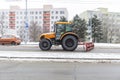 Brno_Czech Republik_february_8_2021_ one yellow tractor with a plow driving down the street in the city and shoveling snow and