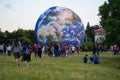 Brno, Czechia - July 12, 2020: People walking in front of inflatable Earth model placed on green grass meadow near planetarium