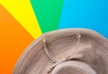 Broad brimmed women`s straw hat on rainbow multicolored pinwheel striped sunburst background. Summer vacation fashion