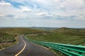 A broad and flat asphalt road on the grassland leads to the top of the mountain