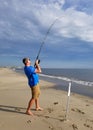 Broadkill Beach, Delaware, U.S.A - May 16, 2022 - A man reeling a big fish using a long surf fishing rod