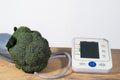 broccoli  and blood pressure meter on a wooden table and white background Royalty Free Stock Photo