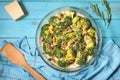 Broccoli cheddar egg casserole in baking dish on blue wooden background