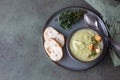 Broccoli cream soup decorated with thyme, cream, roasted cauliflower and fresh bread on green concrete background. Healthy Royalty Free Stock Photo