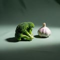 A broccoli floret and a bulb of garlic are placed on a smooth, green surface Royalty Free Stock Photo