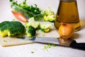 Broccoli, onion, knife and olive oil on kitchen board