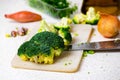 Broccoli, onion, garlic and knife on kitchen board