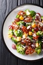 Broccoli salad with cheddar cheese, grapes, bacon, almonds and onions close-up in a plate. Vertical top view