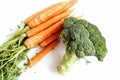Broccoli and some carrots are on a white background. Edible still life