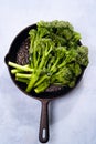 Broccolini fresh organic broccoli florets green vegetable baby broccoli, olive oil, sesame seeds in cast iron pan, vegan raw