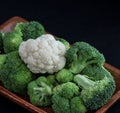 Brocolli and 1 cauliflower floret in a wooden bowl