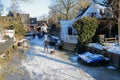 Winter snow and people ice skating on frozen canals in Broek in Waterland, a small town with traditional old and painted wooden ho