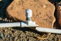 Broken above-ground PVC irrigation pipe line. Sprinkler head with cap