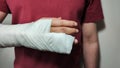 Broken arm, fingers. A white man in a red T-shirt with a cast on his arm. Royalty Free Stock Photo