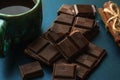 Broken bar of chocolate, cinnamon and cup of coffee an black table, close up Royalty Free Stock Photo