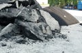 Broken big parts of damaged asphalt coat and crushed stones from old road