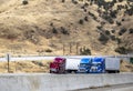 Broken big rig semi truck with open hood standing on the highway road shoulder beside the two semi trucks with semi trailers