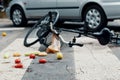 Broken bike and fruits on pedestrian lines after traffic incident with a car