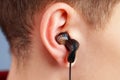 Broken black earphones in the ear of a loud music listener