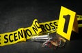 Broken bottle, yellow tape and evidence marker on black slate table, closeup. Crime scene
