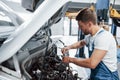 Broken car. Employee in the blue colored uniform works in the automobile salon