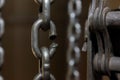 Broken chain link of a manual winch in an old factory building. Dark background.