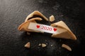 Broken chinese fortune cookie with 2020 and red hearts on the paper slip on a dark background with copy space, new year concept, Royalty Free Stock Photo