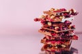 Broken chocolate bars decorated with nuts and raspberry on pink