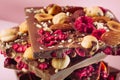 Broken chocolate bars with nuts and sublimated raspberry on pink