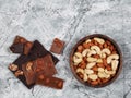 Broken chocolate bars and raw cashew and almonds on gray stone background