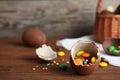 Broken chocolate Easter egg with candies on wooden table. Royalty Free Stock Photo