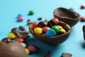 Broken chocolate eggs with candies on light blue background, closeup Royalty Free Stock Photo
