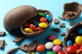 Broken chocolate eggs with candies on light blue background, closeup Royalty Free Stock Photo