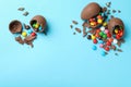 Broken chocolate eggs with candies on light blue background, flat lay. Space for text Royalty Free Stock Photo