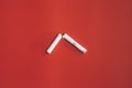 Broken cigarette in half on red background