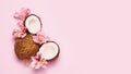 Broken coconut with tropic flowers on pink background