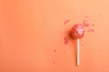 Broken coral lollipop and crumbs on color background