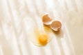 Broken and cracked brown chicken eggshell and raw egg on pastel yellow background Royalty Free Stock Photo