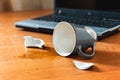 Broken cup and spilled tea or coffee near laptop in the office Royalty Free Stock Photo