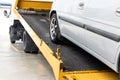 Broken down car towed onto flatbed tow truck with hook cable Royalty Free Stock Photo