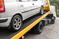 Broken down car towed onto flatbed tow truck with hook cable Royalty Free Stock Photo
