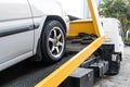 Broken down car towed onto flatbed tow truck with hook cable Royalty Free Stock Photo